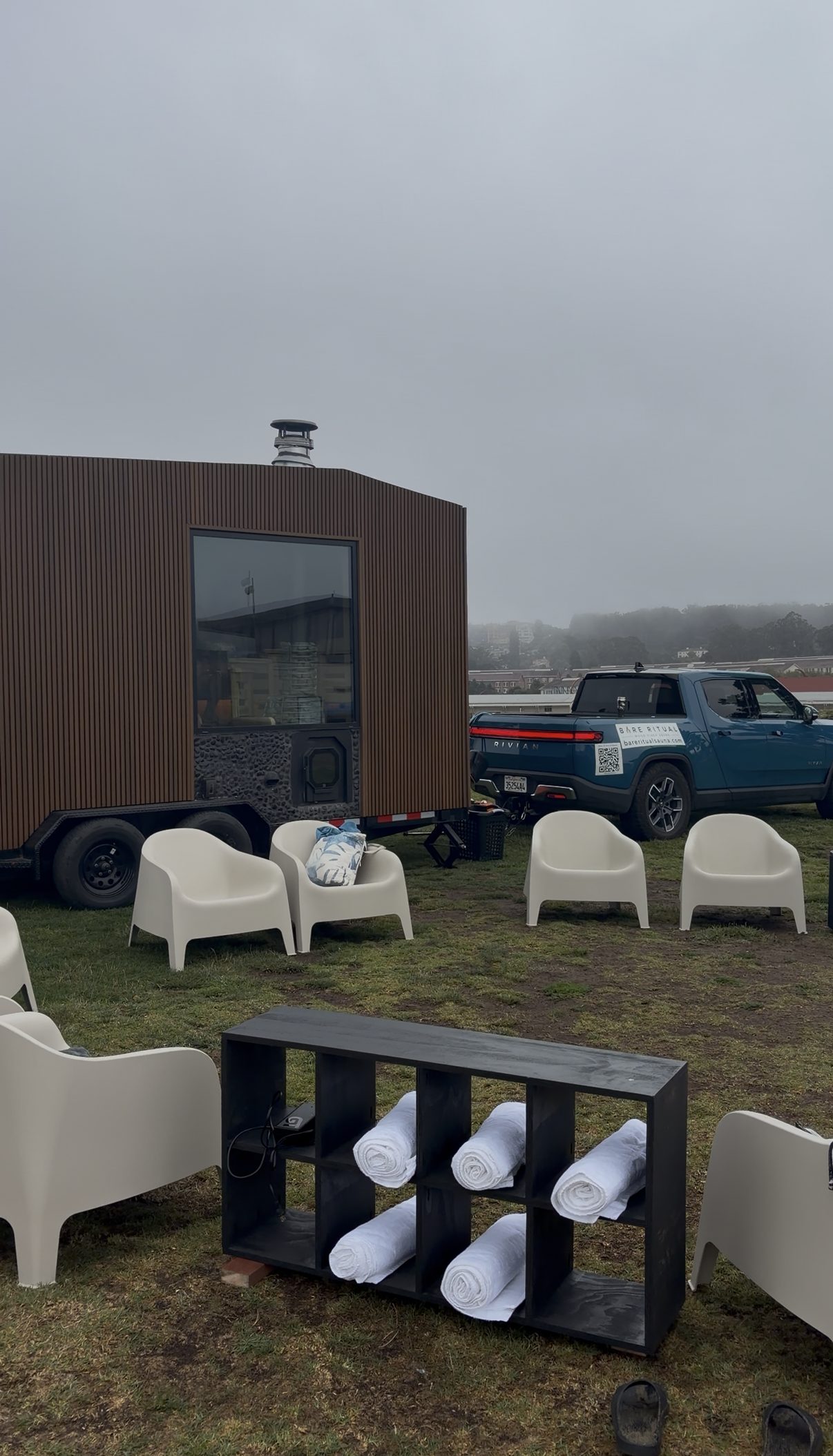 The Bare Ritual mobile wood-fired sauna set up with chairs and towels