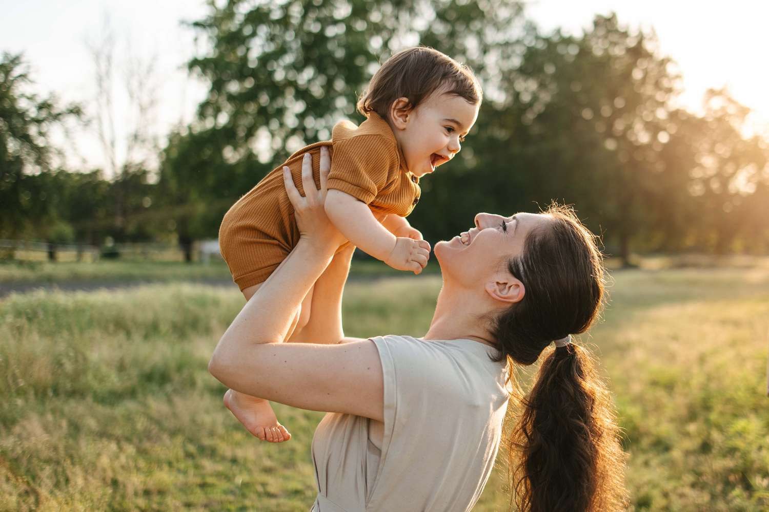 Mother lifting her baby outdoors