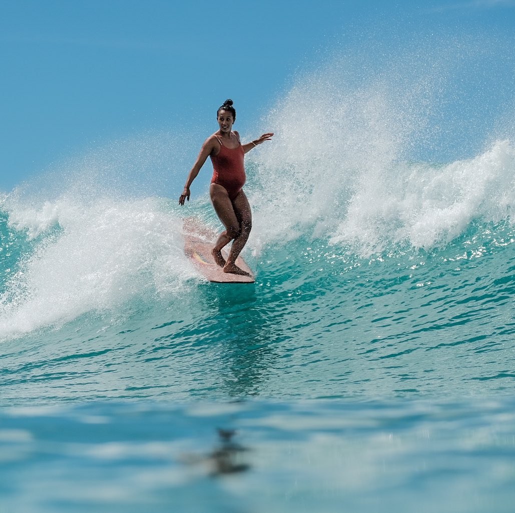 Pregnant surfer riding a wave